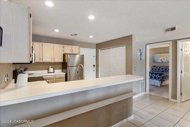 kitchen with kitchen peninsula, appliances with stainless steel finishes, a textured ceiling, and light tile patterned flooring