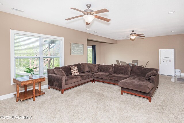 living room with a ceiling fan, light colored carpet, and baseboards