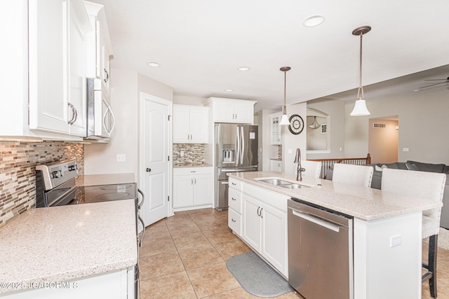 kitchen with stainless steel appliances, a sink, a kitchen breakfast bar, decorative backsplash, and white cabinetry