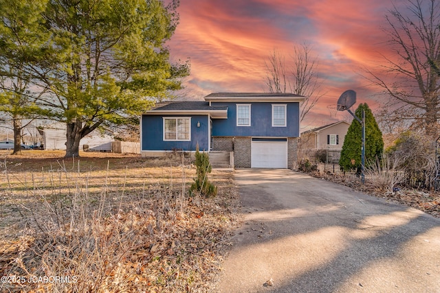 tri-level home featuring brick siding, concrete driveway, and a garage