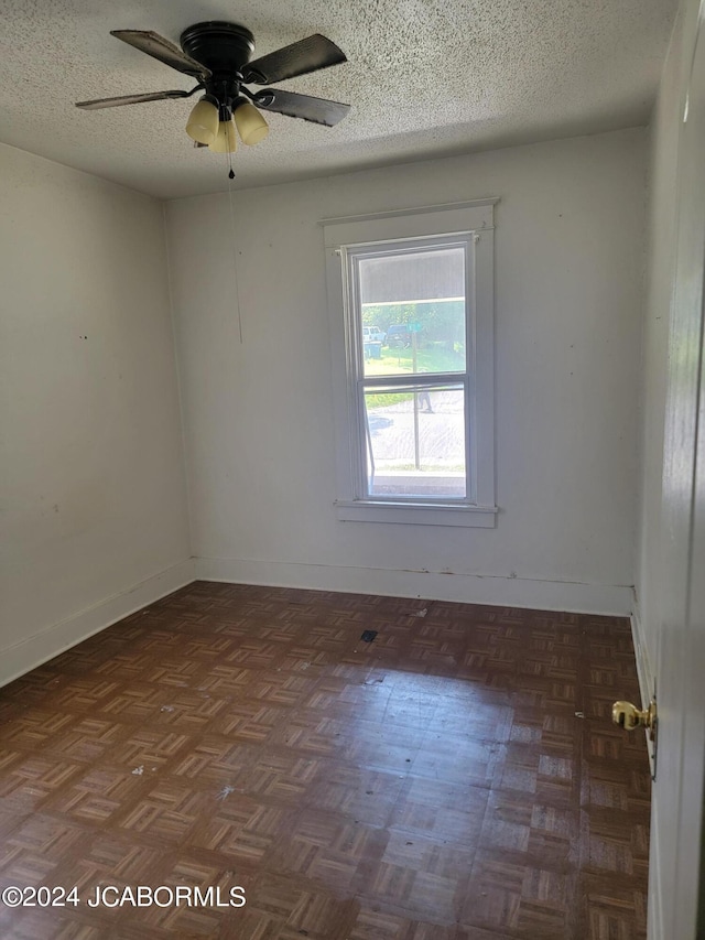 empty room featuring dark parquet flooring, a textured ceiling, and ceiling fan