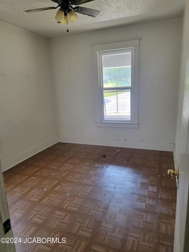 unfurnished room featuring ceiling fan, dark parquet flooring, and a textured ceiling