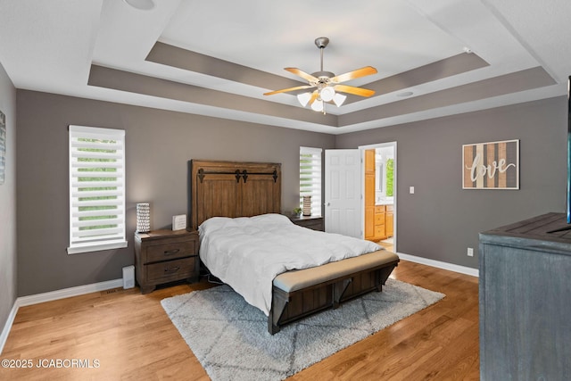 bedroom with baseboards, multiple windows, and a raised ceiling