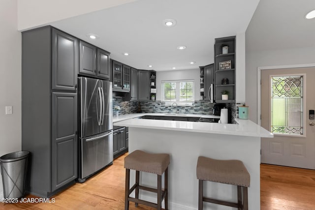 kitchen with open shelves, appliances with stainless steel finishes, a peninsula, and a breakfast bar