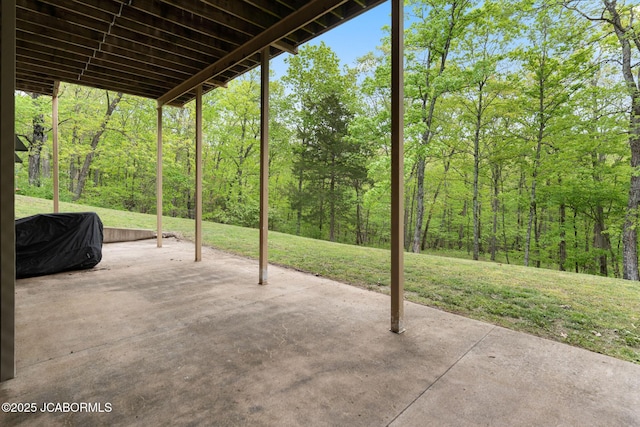 view of patio featuring a view of trees and a grill