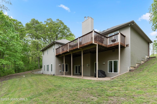 rear view of property with a patio, a wooden deck, a yard, and a chimney