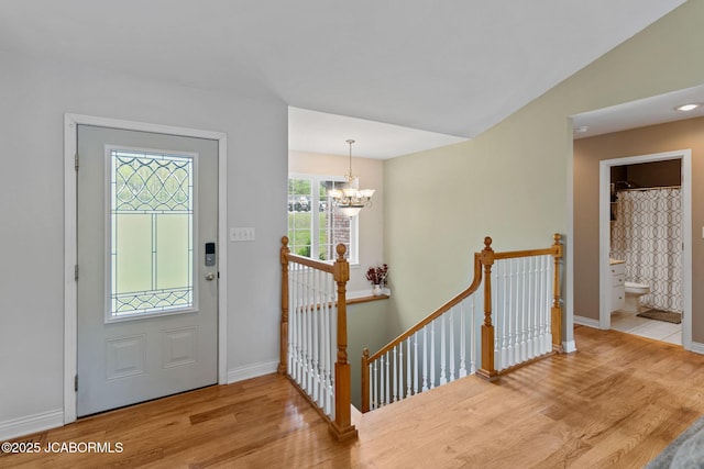 entryway featuring baseboards, a chandelier, and wood finished floors