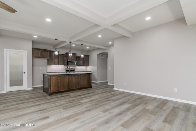 1502 Summerfield Dr, Jefferson City, MO 65109 - kitchen with stainless steel microwave, beamed ceiling, dark brown cabinetry, baseboards, and light wood-type flooring