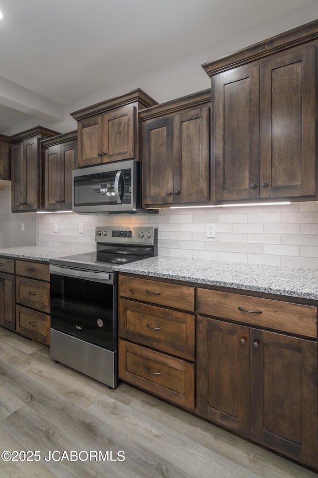 1502 Summerfield Dr, Jefferson City, MO 65109 - kitchen with stainless steel appliances, light wood-style floors, decorative backsplash, light stone countertops, and dark brown cabinetry