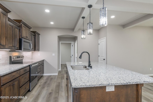 1502 Summerfield Dr, Jefferson City, MO 65109 - kitchen featuring appliances with stainless steel finishes, a sink, beam ceiling, light wood finished floors, and an island with sink
