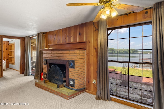24671 Gardner Rd, Versailles, MO 65084 - unfurnished living room with a water view, carpet floors, a fireplace, a ceiling fan, and wooden walls