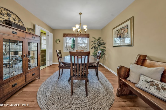 dining room with light wood-style flooring, a notable chandelier, french doors, and baseboards