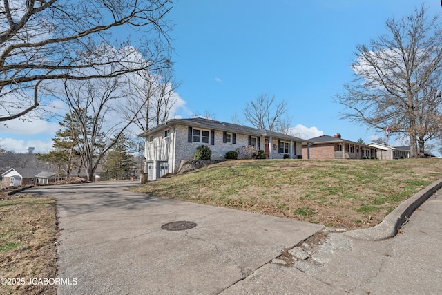 ranch-style house with brick siding, driveway, an attached garage, and a front lawn