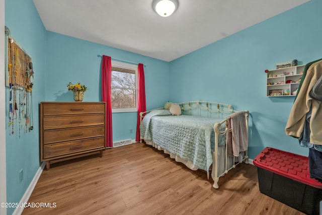 bedroom with visible vents, baseboards, and wood finished floors