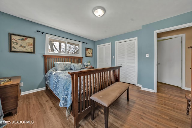 bedroom with baseboards, multiple closets, and wood finished floors