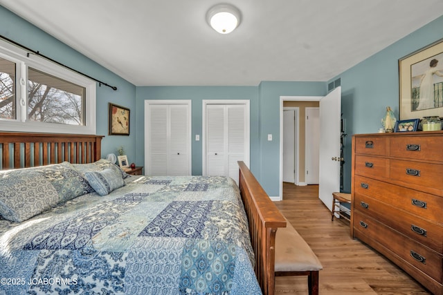 bedroom with visible vents, multiple closets, and wood finished floors