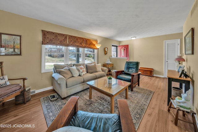 living room featuring visible vents, baseboards, and light wood-style floors