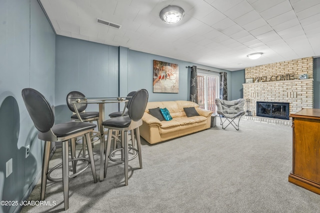 living room featuring visible vents, a fireplace, and carpet flooring