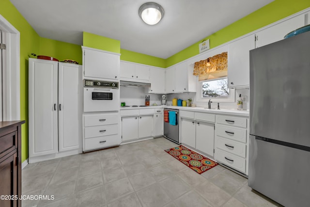 kitchen with a sink, light countertops, white cabinets, appliances with stainless steel finishes, and under cabinet range hood