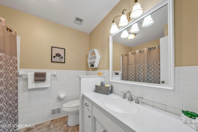 bathroom with visible vents, tile walls, a chandelier, toilet, and vanity