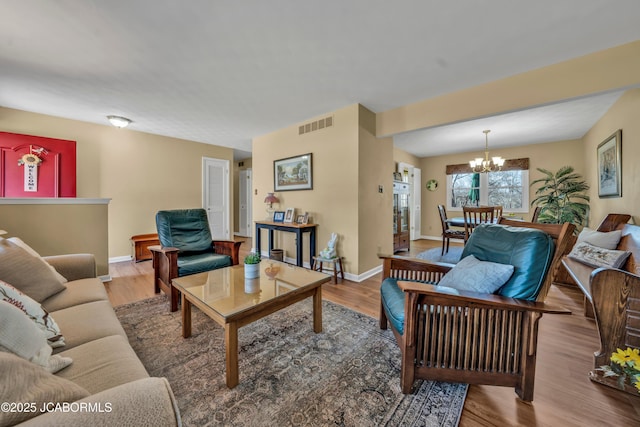 living room featuring visible vents, baseboards, wood finished floors, and a chandelier