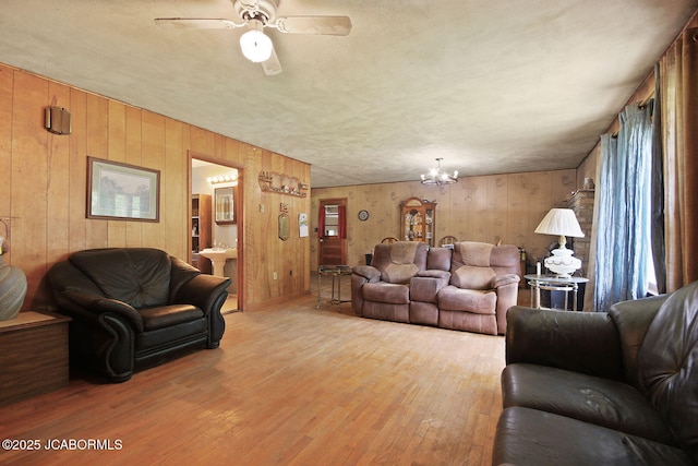 29074 E St, Lincoln, MO 65338 - living room featuring light wood finished floors, wood walls, ceiling fan, and a chandelier