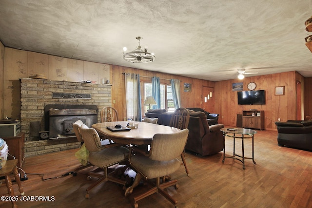 29074 E St, Lincoln, MO 65338 - dining area featuring wood finished floors, wooden walls, a chandelier, and a fireplace with raised hearth
