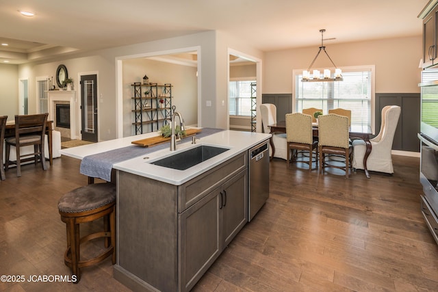 kitchen featuring dishwasher, dark wood-style floors, a notable chandelier, and a sink