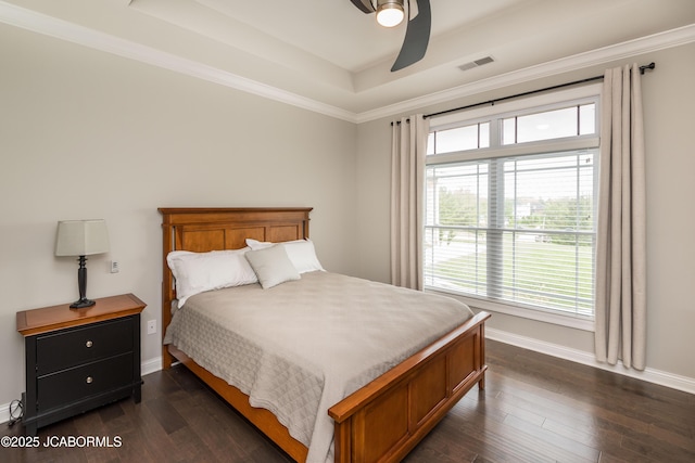 bedroom featuring dark wood-style floors, ceiling fan, a tray ceiling, baseboards, and visible vents