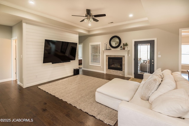 living room featuring baseboards, dark wood-style flooring, a ceiling fan, and a raised ceiling