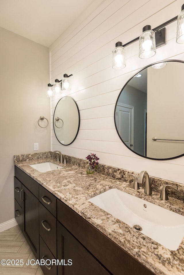 full bath with baseboards, a sink, and double vanity