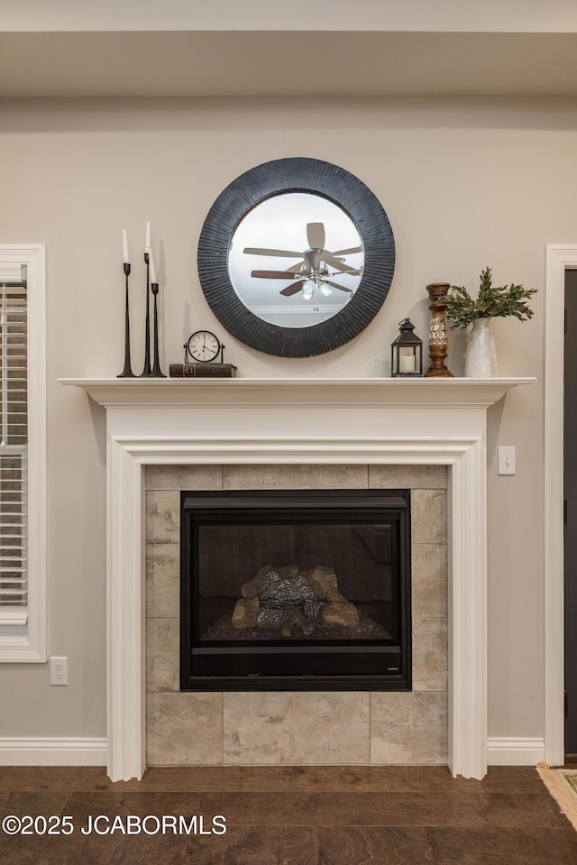 room details featuring a tile fireplace, baseboards, and wood finished floors