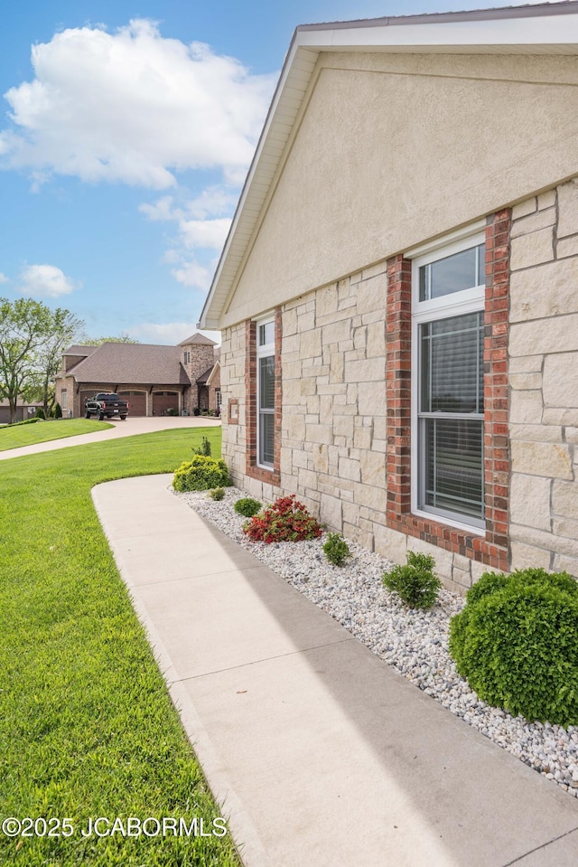 view of side of home featuring a yard, stone siding, and stucco siding
