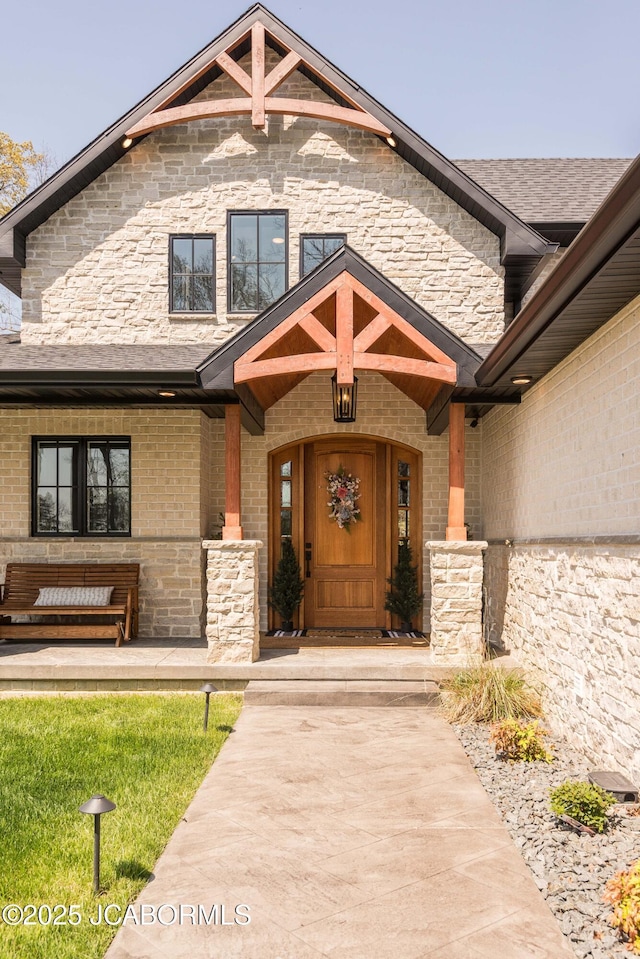 entrance to property with brick siding, a porch, and stone siding