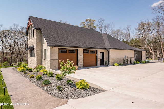 view of side of property with a garage, brick siding, roof with shingles, and concrete driveway