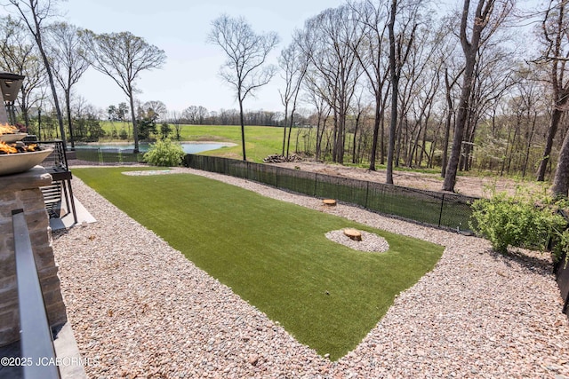 view of yard with a fenced backyard and a water view