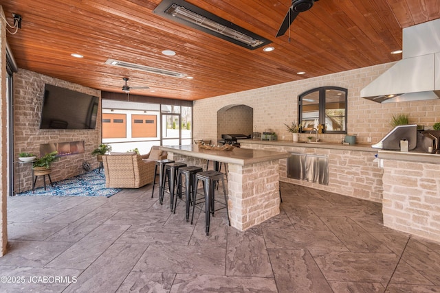 view of patio with exterior fireplace, outdoor wet bar, a ceiling fan, and area for grilling