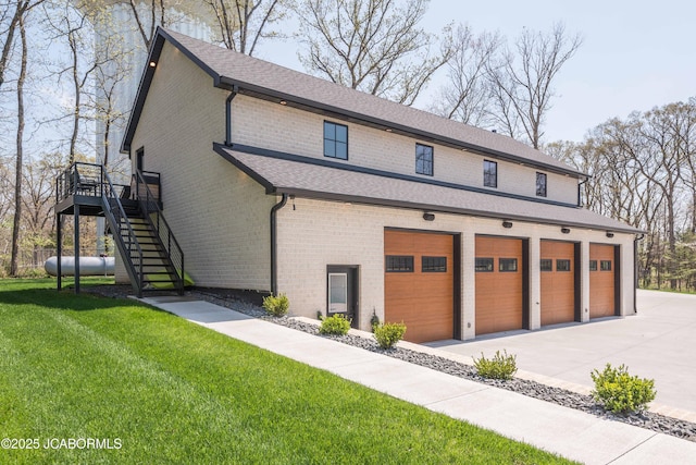 exterior space featuring stairway, concrete driveway, a front lawn, a garage, and brick siding