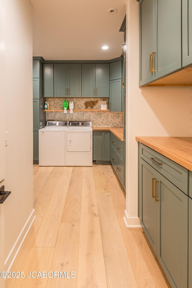 kitchen featuring light wood-style floors, green cabinetry, decorative backsplash, and separate washer and dryer