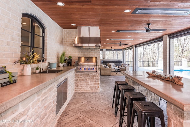 kitchen with a sink, recessed lighting, a ceiling fan, wall chimney range hood, and wooden ceiling