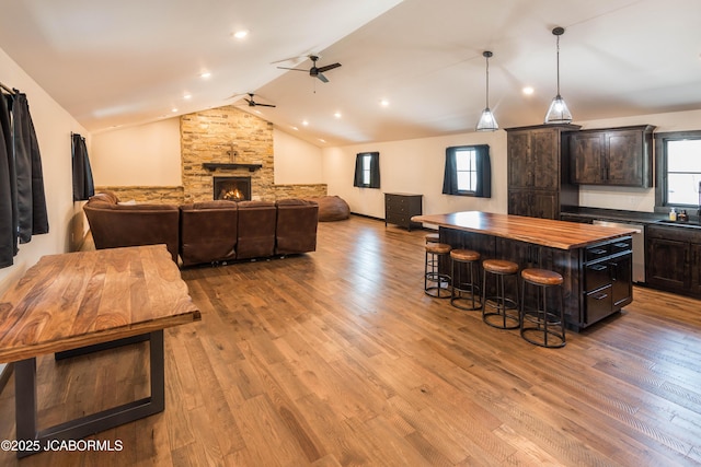 kitchen featuring a center island, a kitchen breakfast bar, vaulted ceiling, butcher block countertops, and a ceiling fan