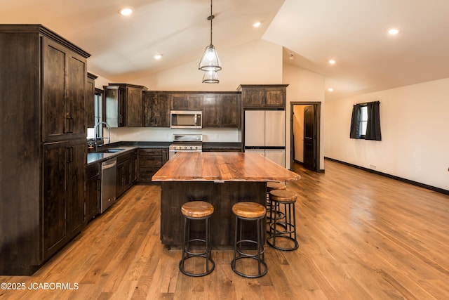 kitchen with butcher block counters, dark brown cabinetry, stainless steel appliances, and a sink