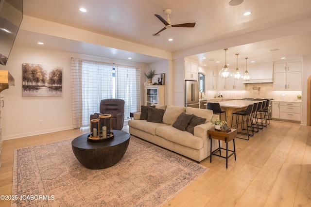 living room featuring a ceiling fan, baseboards, recessed lighting, and light wood-style floors