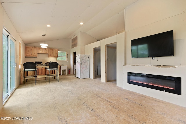 living area with a glass covered fireplace and vaulted ceiling