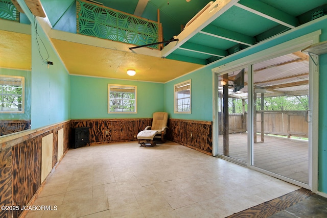 unfurnished room with beam ceiling, wainscoting, and wooden walls