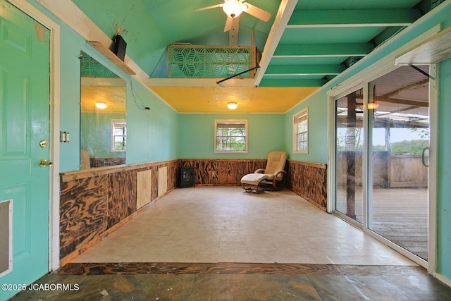 unfurnished room featuring wood walls, a wainscoted wall, ceiling fan, and vaulted ceiling