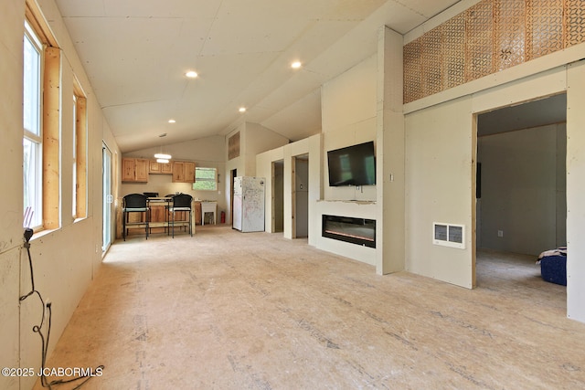 unfurnished living room featuring a glass covered fireplace, visible vents, recessed lighting, and vaulted ceiling