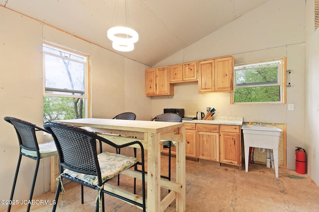 kitchen with light brown cabinetry and lofted ceiling