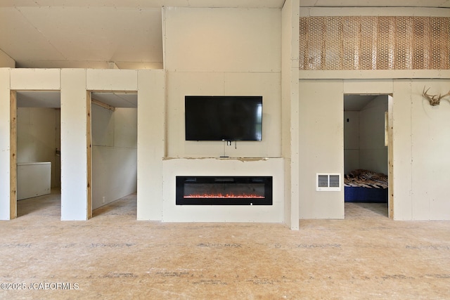 unfurnished living room featuring visible vents and a glass covered fireplace