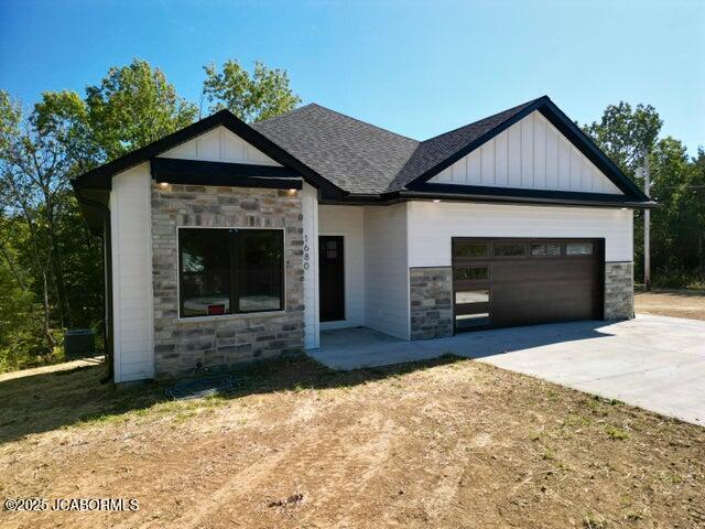 1680 W Fenton Rd, Columbia, MO 65202 - view of front of home featuring driveway, board and batten siding, stone siding, a shingled roof, and an attached garage